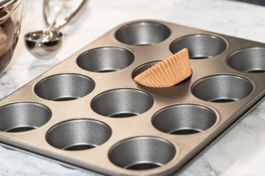 Lezzetli çikolatalı kekler yapmaya hazırlanırken, kek tepsisini kağıt kalemlerle dikkatlice diziyoruz, lezzetli bir ikram bizi bekliyor..