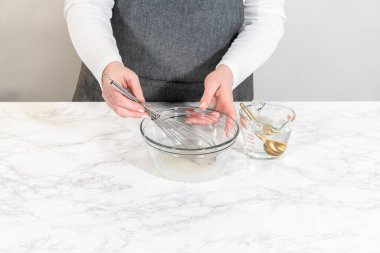 Cam kasede krema karıştırırken elleri çırpı çırpıyor. Paskalya Kurabiyesi Sandviçi için ahududu kremalı dondurma hazırlama sürecinin bir parçası..