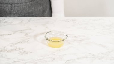 Küçük bir kase taze sıkılmış limon suyu, limonlu kurabiye yapımında kullanılmaya hazır. Bu bileşen hamura narenciye tadı katıyor..