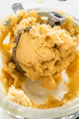 Klasik Şekerli Kurabiye Hamuru 'nun karıştırma kabında yakın plan görüntüsü kremalı ve hamurun karışık dokusunu gözler önüne seriyor. Bu basamak tereyağı, şeker ve diğer maddeleri birleştirerek pürüzsüz bir madde oluşturur.