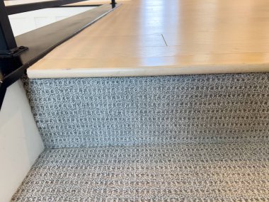 Merdivenin en üst basamağında modern korkuluk sisteminin bir parçası olan desenli bir halı ve doğal ahşap kaplama var. Döşeme ve merdiven tasarımı için kullanışlı.