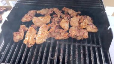 Salamura edilmiş tavuk butları küçük bir Weber ızgarasının ızgarasında cızırdar, havayı iştah açıcı bir koku ve hafif bir dumanla doldurur..