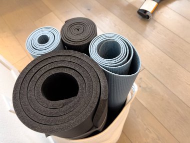 Yuvarlak yoga minderlerinin doğrudan üst görüntüsü yumuşak gri ve koyu kömür tonlarında, beyaz bir sepette düzenlenmiş..