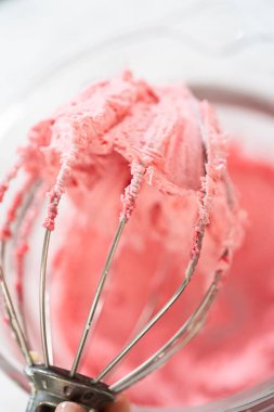 Bir el çırpıcının çırpıcısını taze çırpılmış yaban mersinli tereyağıyla tutar. Pürüzsüz, havadar dokusu ve canlı pembe tonu kurabiyeler ve pastalar için mükemmel bir dolgu ya da krema haline getiriyor..