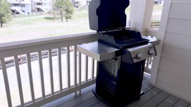 Paslanmaz çelik yan rafı ve çift brülör kontrollü bir Glean gaz ızgarası kapalı bir veranda güvertesine yerleştiriliyor. Izgara, açık ahşap panelli ve manzaralı bir duvar karşısında duruyor.