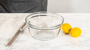 Bir cam kase ve bir zester taze limonların yanına konur, limon spritz kurabiyelerine narenciye aroması eklemeye hazırdırlar..