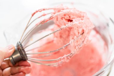 Bir el, ahududulu tereyağlı kremayla dolu bir çırpı çırpısı tutar. Paskalya Kurabiyeli ve ahududulu tereyağlı sandviç için taze çırpılmış..