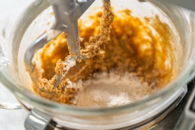 Yukarıdan yakından bakınca tezgahın karışımına kuru malzemelerin eklendiğini görüyoruz. Un ve baharatlar kasede görülüyor. Amber zencefilli ekmeğin karıştırma işlemine devam ediliyor.