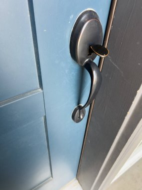 Modern bir mat siyah kapı kolu ve eğri bir tasarım donanma renkli bir ön kapıya monte edilir. Yakın çekim, temiz ve sağlam formun altını çizer.