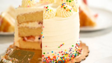 Katmanlar arasında çilek ve yaban mersinli tek bir dilim vanilyalı pastadan alınır. Altın levha ve beyaz mermer yüzey pastaların iç kısımlarını renklendiriyor..