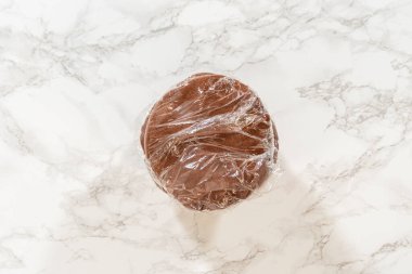 Soluk zencefilli kurabiye hamurunu plastik bir tezgaha sarmalayıp ince baharat aromalı Soluk Zencefilli Kurabiye Kurabiyeleri 'ne koyun. Hamur pürüzsüz ve düzgün, soğutmaya hazır..