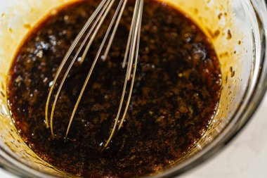 Pekmez, yumurta ve portakal aromalı kurabiye hamuru için cam bir kasede çırpılmış. Karışım, parlak turuncu tat benekleri olan koyu, zengin bir renge sahip, dengeli bir renk oluşturuyor.