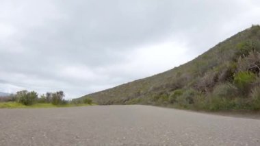 Bu sakin kış sahnesinde, bir araç dikkatle Los Osos Vadisi Yolu ve Montana de Oro Eyalet Parkı 'ndaki Pecho Vadisi Yolu boyunca ilerliyor..