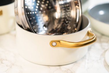 Parlak, paslanmaz çelik bir buhar sepetiyle dolu seramik tencere, uyumlu tencerelerin yanında stil verilmiş. Ev ve yaşam tarzı ürünleri için harika..