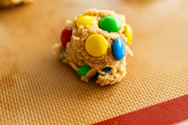 Parker, Colorado, 1 Temmuz 2025 üzerinde kırmızı, sarı ve yeşil çikolatalı fındık ezmeli kurabiye hamuru. Hamur topu silikon bir paspasın üzerinde, sıcacık bir mutfakta..