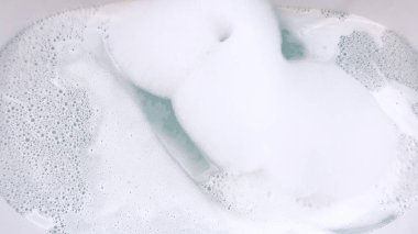 Zarif, suyla dolu beyaz bir küvet, içinde zarif, fırçalanmış nikel bir musluk ve küvete yavaşça akan su var. Küvetler modern tasarım ve berrak, sakin su huzurlu bir yer olduğunu gösteriyor.