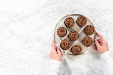 Düz yatıyordu. Taze pişmiş kekler ustaca zengin karamel ile dolduruldu ve kadife çikolatalı şekerlemeyle süslendi. Hepsi de el değmemiş beyaz servis tabağında zarif bir şekilde sunuldu..