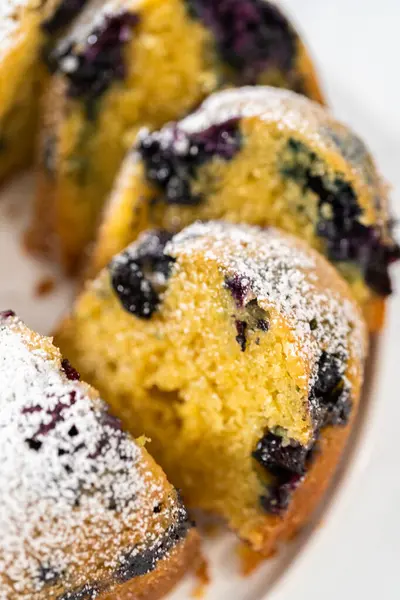 Taze pişmiş limonlu yaban mersinli kek dilimliyorum. Pudra şekerli..