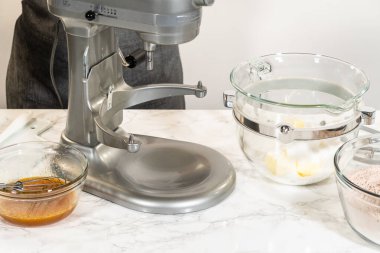 Tereyağı, esmer şeker ve ince baharatlı zencefilli kurabiyeler için diğer malzemelerle karıştırın. Mikserdeki cam kase kısmen dolu..