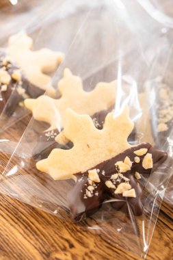 Dikkatlice paketlenmiş Noel kurabiyeleri, çikolataya batırılmış ve şeffaf selofan ambalajla sunulmuş, bayram hediyesi olarak mükemmel..