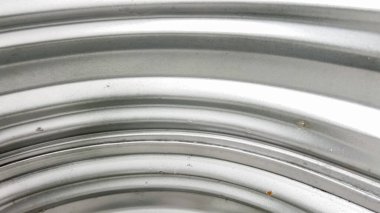 Yakın plan çekimler, bodrum katındaki bir pencerenin kıvrımlı çelik panellerinde küçük pas izleri ve yaşlanma işaretlerini vurguluyor. Bu çıkıntılı metal yumuşak ortam ışığını yansıtıyor..