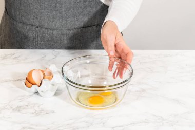 Klasik Şekerli Kurabiye Hamuru için cam bir kase içinde, içinde çırpılmış çırpı olan sıvı bileşenlerin yakın görüntüsü. Malzemeler adım adım bir mermer tezgahta hazırlanır.