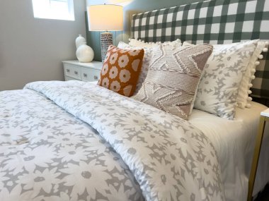 Yatak odası dekorunda desenli yastıklar ve kareli yatak başlığı. Tarafsız mobilyalar ve yaşam tarzı ve iç tasarım kullanımı için hafif ışıklandırma ile biçimlendirilmiş.