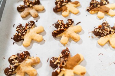 Çikolataya batırılmış ve fındık ezmesi ile süslenmiş kar tanesi şeklindeki kesme şekerli kurabiyeler yaratmak. Parşömen üzerinde zarif bir şekilde sunulmuş..