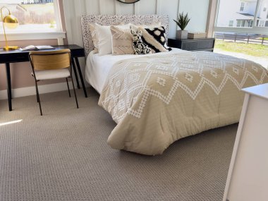 Üzerinde altın lamba ve ahşap sandalye olan küçük siyah bir masa, rahat bir yatak odasının penceresinin yanında, tarafsız bir yatağın yanında, desenli bir yatağın yanında oturur..