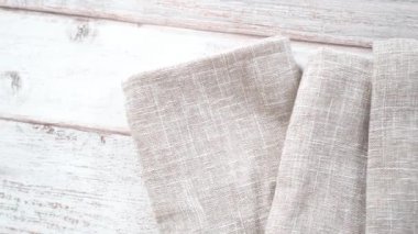 Yeni keten yemek peçetesini beyaz ahşap bir masada katlıyorum..