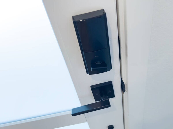 A close up of a modern black door handle with lock on a white door. The design is sleek, minimal, and functional.