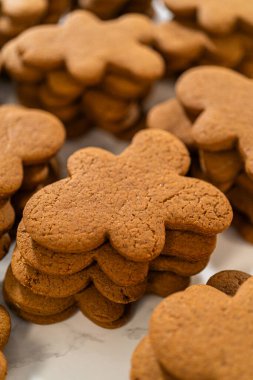 A stack of freshly baked gingerbread man cookies, highlighting their golden-brown color and classic holiday shape, ready for decorating.