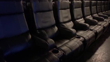 Colorado Springs, CO, USA-079 - 20 Haziran 2024 - Sıralar halinde sıralanmış deri koltukları ve mor duvarları olan boş modern bir sinema salonunda geniş ve yakın çekim serisi. Yazı işleri için ideal