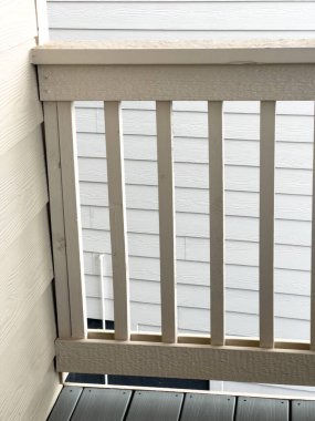 Dikey ahşap korkulukları ve gri döşeme tahtaları olan küçük bir balkon köşesi temiz bir modern görünüm sunuyor. Mimari bloglar, güvenlik korkulukları ve kiralık mülk promosyonu için ideal.