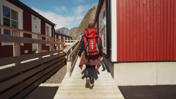 在传统的红色罗布的背景下 年轻美丽的女旅行家来到了木制码头 来到了挪威的Lofoten — 图库视频影像