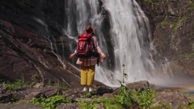 Sırt çantalı güzel Asyalı kadın gezgin şelale manzarasına bakıyor muhteşem manzara ve orman, seyahat özgürlüğü yaşam tarzı konsepti.