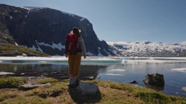 Norveç 'in Lofoten tepelerinde kar manzaralı dağ manzaralı kırmızı sırt çantalı aktif bir kadın. Güneşli bir gün