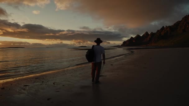 Ένας Τύπος Καπέλο Σακίδιο Περπατά Στο Ηλιοβασίλεμα Στη Θάλασσα Και — Αρχείο Βίντεο