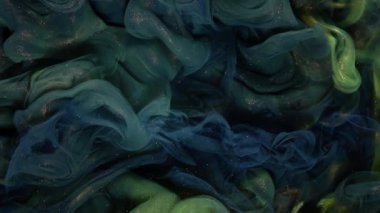 Yeşil ve sarı boya, siyah bir arkaplana karşı suya sıçrar renkli mürekkep renkli bir bulut gibi yayılır ve patlar floresan ışık ve doğal parıltı gibi. Yavaş çekim, 4K.