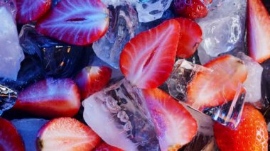 Buz küplerindeki taze çileklerin üzerine düşen buz parçaları, siyah arka plandaki doğal ve organik meyveler..