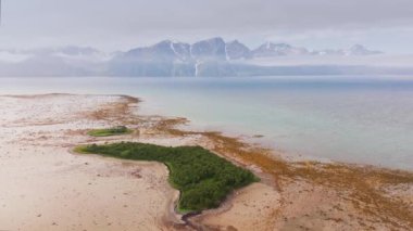 Issız kumsal sahili ile gök mavisi deniz suyu arasında Myrland Sahili, Flakstadoy, Lofoten Adaları, Norveç 'teki dağlara karşı hava hareketi.