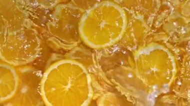 Dilimlenmiş limonlar, portakal ve limonların turuncu arka planda suya düşmesi, limonlu turunçgil meyvesi kokteyli yapmak, soğuk limonata içmek, dilimlenmiş meyveli karbonatlı su içmek,.