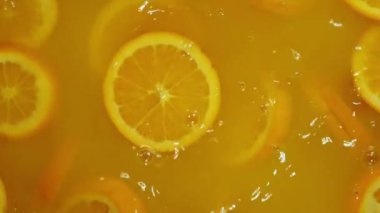 Dilimlenmiş limonlar, portakal ve limonların turuncu arka planda suya düşmesi, limonlu turunçgil meyvesi kokteyli yapmak, soğuk limonata içmek, dilimlenmiş meyveli karbonatlı su içmek,.