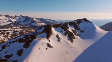 Soğuk bir kış gününde Kuzey yabanda kar kaplı bir dağ sırasının çarpıcı hava manzarası. 4K Hava Videosu.