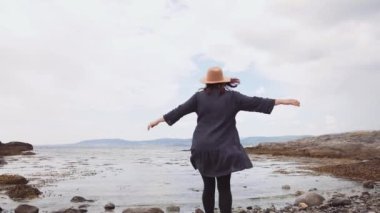Sahilde dans eden kaygısız genç kız. Çiçekli elbiseler giyiyor. Yakından..