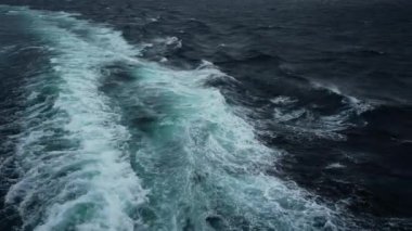 Denizde fırtına. Gemi boyunca yan görüş. Rüzgâr dalgaları püskürtür. Rüzgar beyaz köpükle dalgalanıyor..