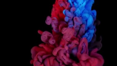 Renkli boyalı üst görüntü yavaş çekimde suda karışıyor. Siyah arkaplanda mürekkep sıvısı var. kırmızı mavi sarı soyutlama