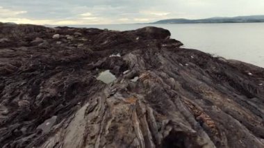 Bulutlu soğuk havada kara volkanik kayalık kıyıların havadan görünüşü. Vahşi doğayı keşfetmek, İzlanda ya da Norveç 'i gezmek