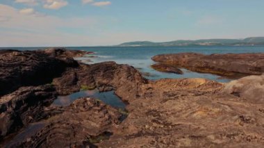 Bulutlu soğuk havada kara volkanik kayalık kıyıların havadan görünüşü. Vahşi doğayı keşfetmek, İzlanda ya da Norveç 'i gezmek