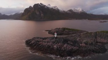 Lofoten adasındaki sahil şeridinde kırmızı çatılı küçük deniz feneri.